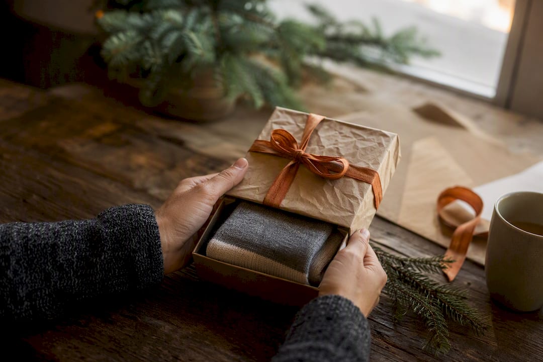 Hands unwrapping luxury cashmere sock gift